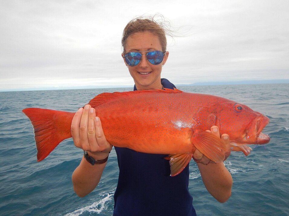 female angler wearing sunglasses holding a coral trout