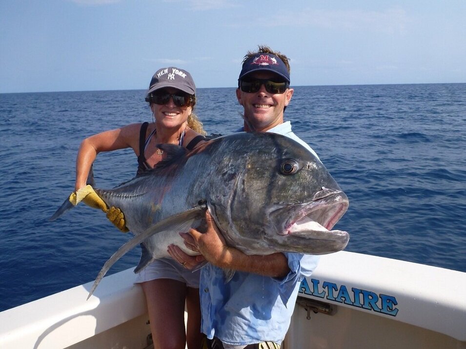 male and female angler holding a giant trevally