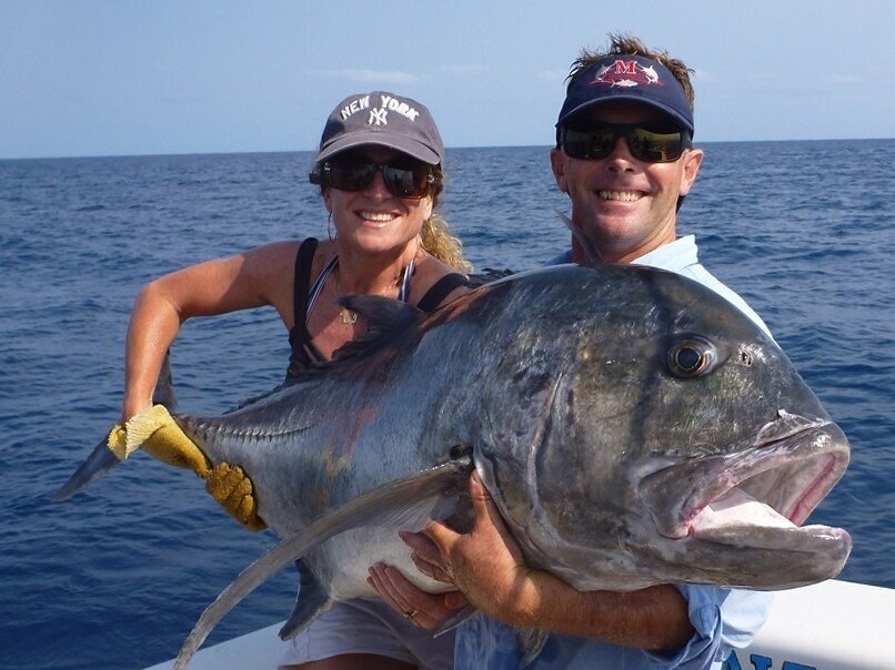 female and male angler holding a giant trevally 