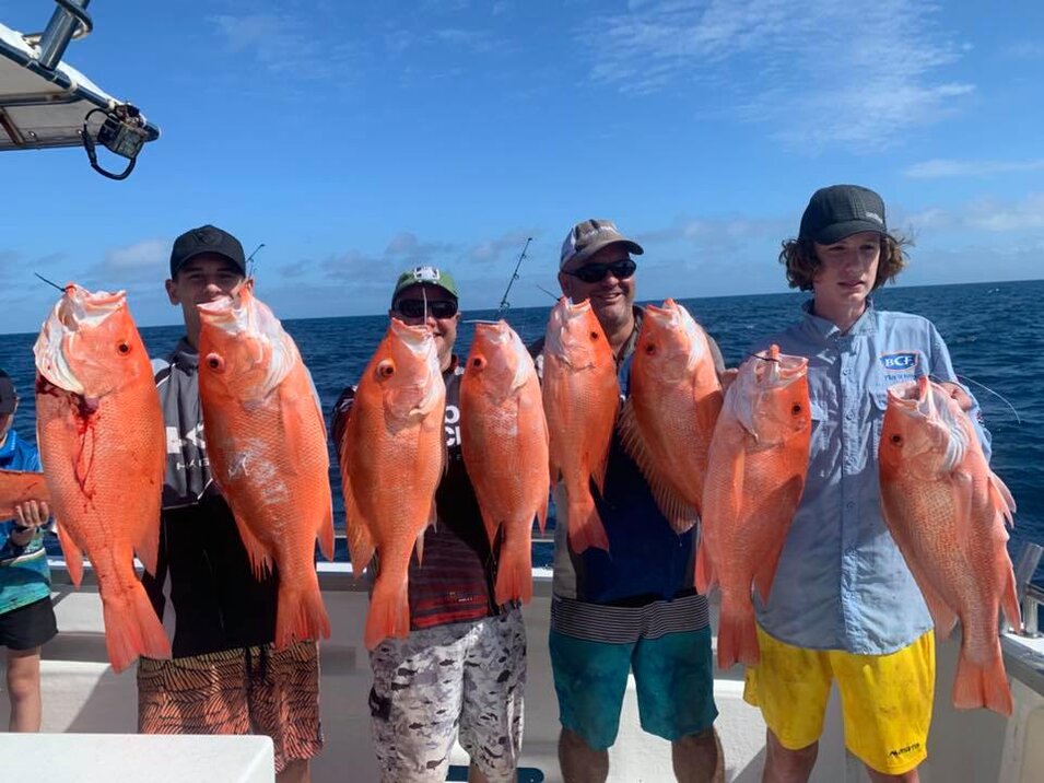 group of male anglers showing their red emperor catch