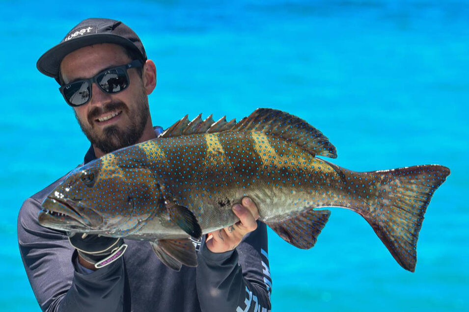 Fisherman with a freshly caught coral trout on the Great Barrier Reef near Port Douglas