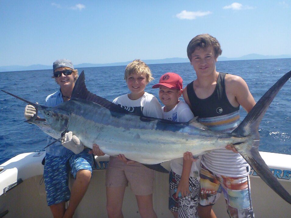 four boys holding a large marlin fish