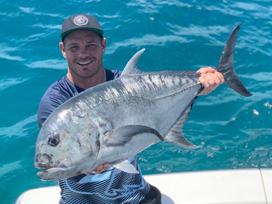 male angler holding a trevally fish