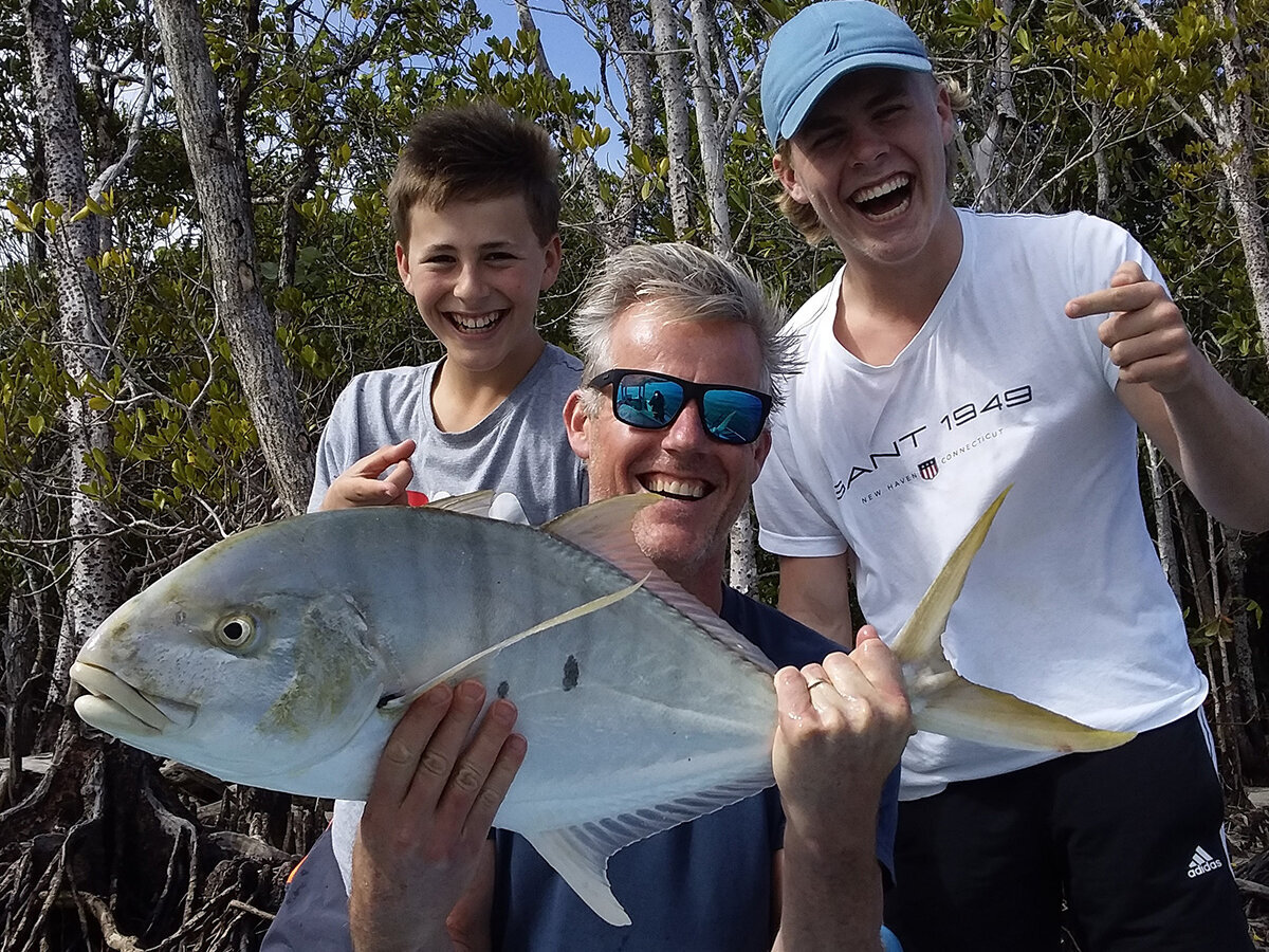 father and two sons presenting their queenfish catch