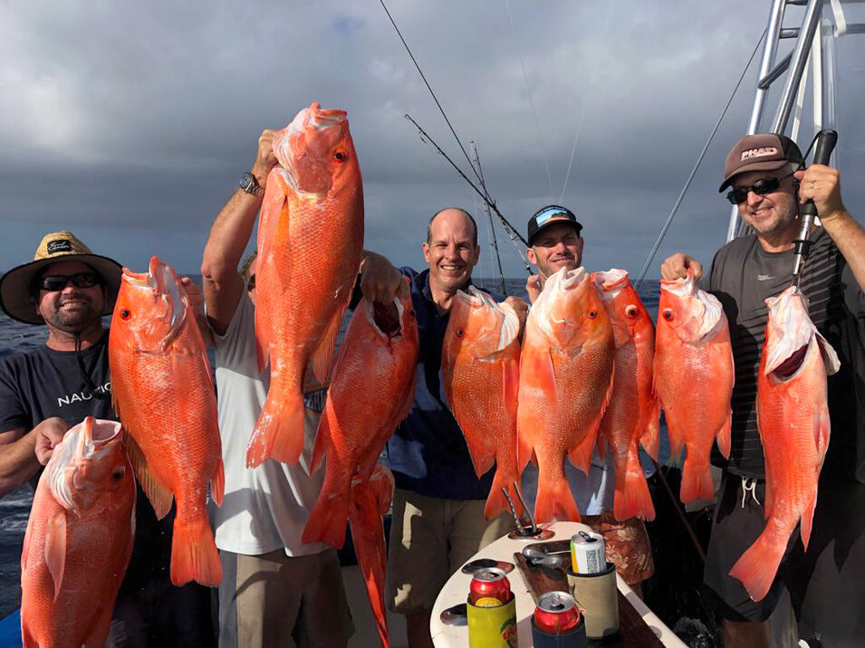 group of male anglers holding up their reef fish catch