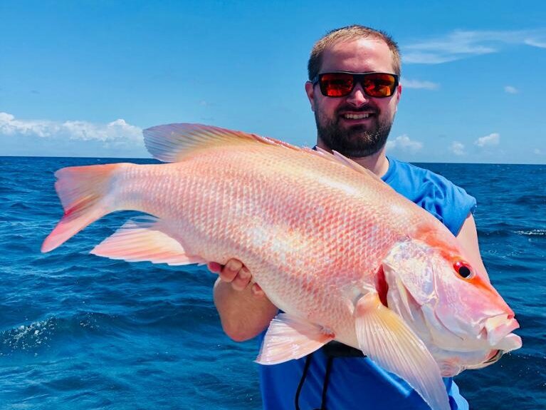 male angler holding a large reef fish