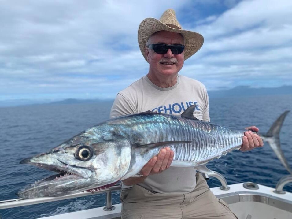 Male angler with grey hair holding a wahoo fish