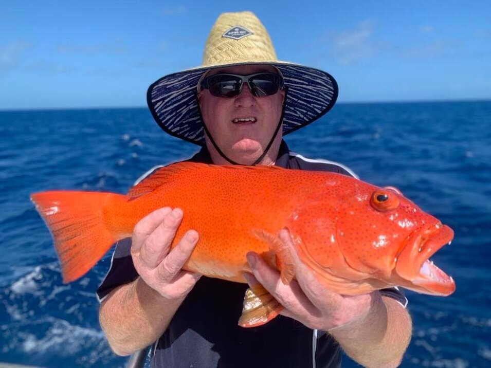 male angler with large hat holding a coral trout