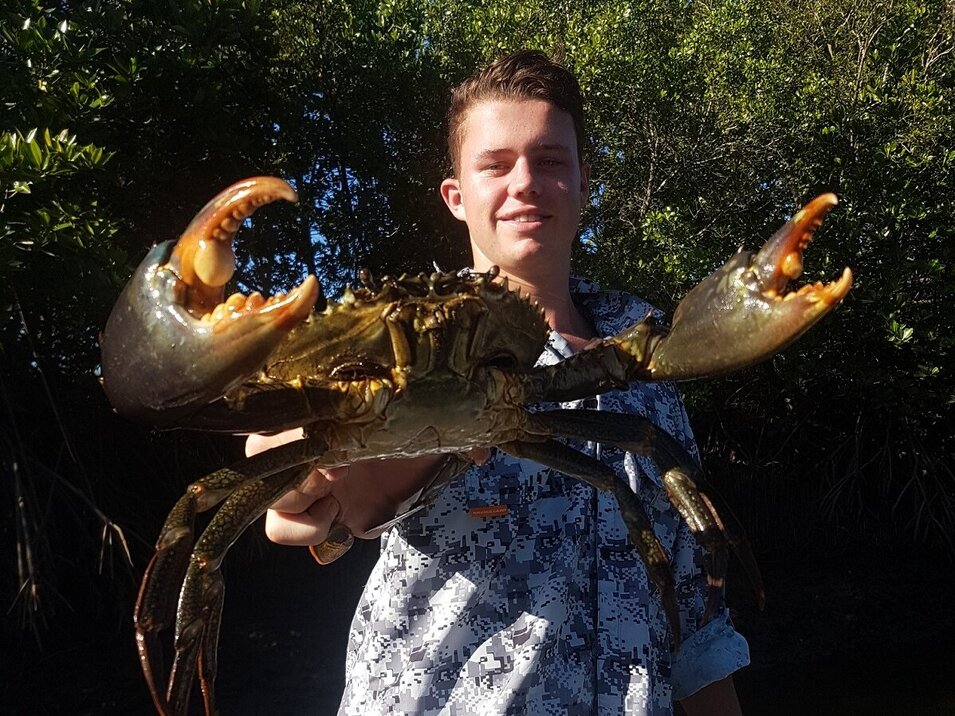 young male angler holding a mud crab