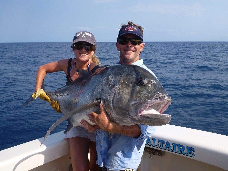 Couple holding a giant trevally during reef popper fishing