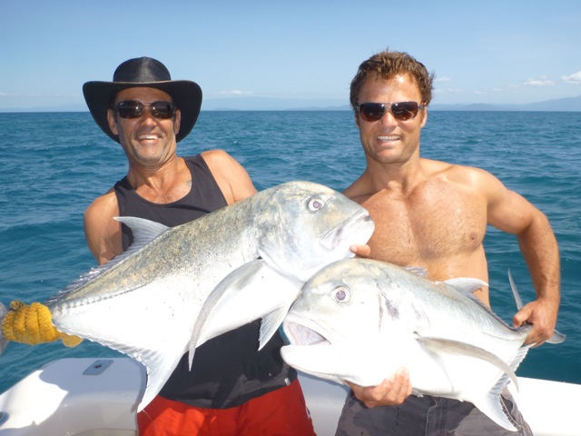 two male anglers posing with their trevally fish