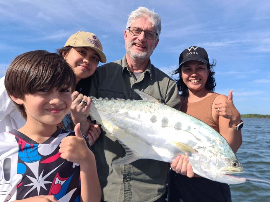 Family holding their freshly caught Queenfish