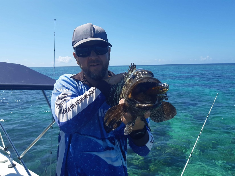 Fisherman with cap showing his Great Barrier Reef fish catch