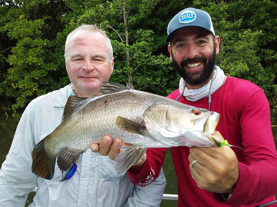 Two happy anglers with a Barramundi fish