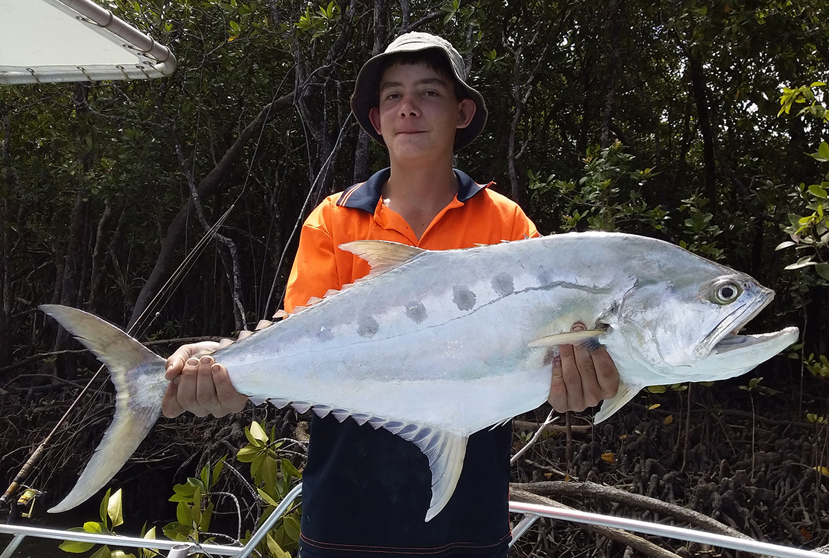 Teen angler holding proudly a Queenfish