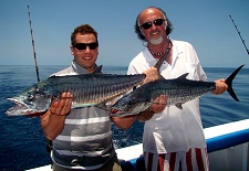 Two happy fishermen holding a spanish mackerel each while reef fishing