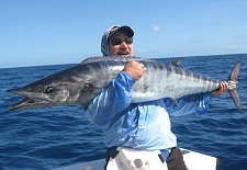 Happy game angler holding a wahoo fish